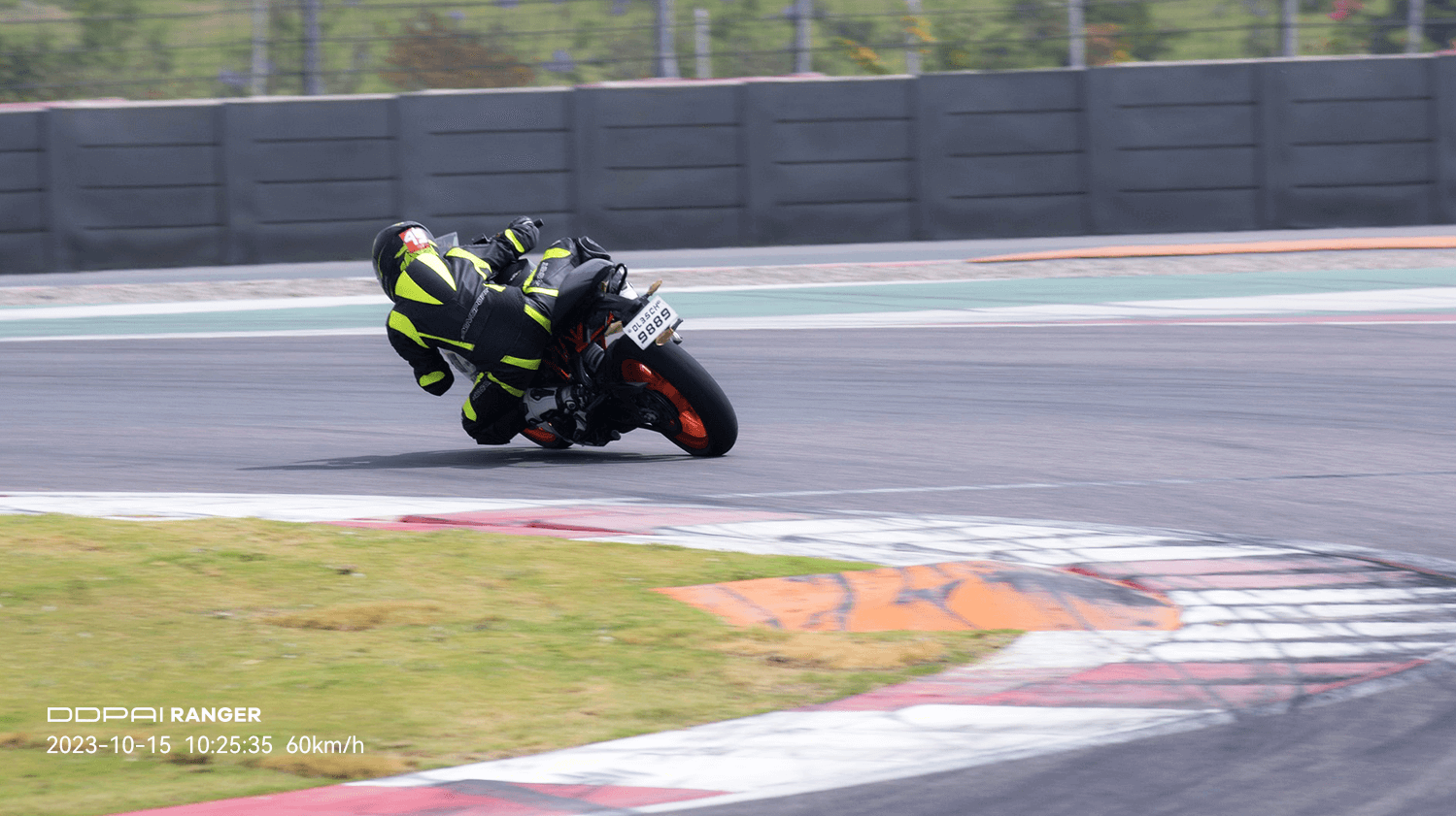 Motorcyclist leaning into a high-speed turn on a racetrack, captured by the Ranger Riding Camera with speed overlay.