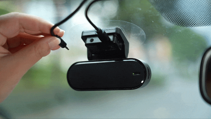 Hand connecting the power cable to the main unit of the dash cam after installing the rear camera.